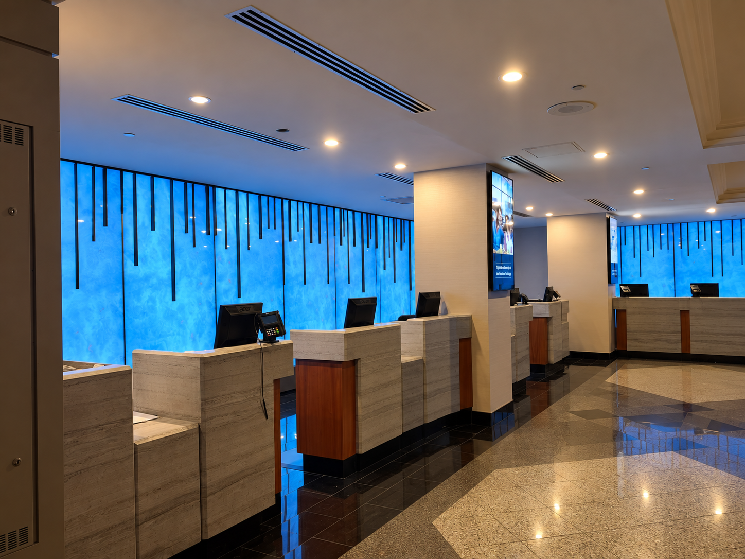 Modern reception lobby with marble-fronted desks and a blue backlit wall